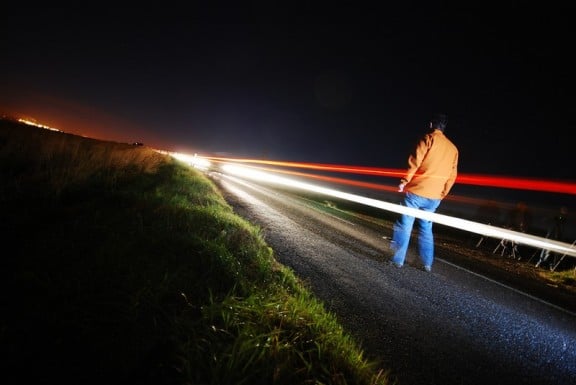 les phares d'une voiture devant un homme sur la route