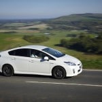 une toyota prius blanche de profil roulant sur la route