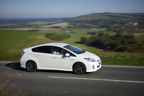 une toyota prius blanche de profil roulant sur la route