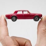 une voiture miniature entre deux doigts