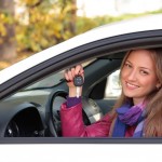 une femme souriante dans sa voiture louée