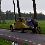 une homme entrain de pousser une 2cv citroen