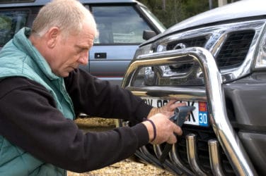 Une personne entrain de poser un autocollant sur sa plaque d'immatriculation