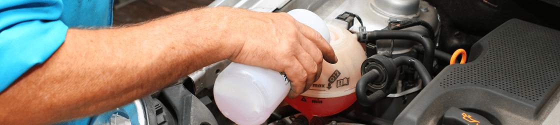 Zoom sur une personne qui ajoute du liquide de refroidissement dans sa voiture