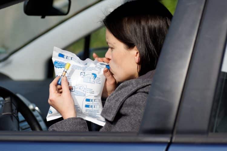 Une femme qui souffle dans un éthylotest à bord de sa voiture