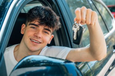 Un jeune conducteur content au volant de sa nouvelle voiture