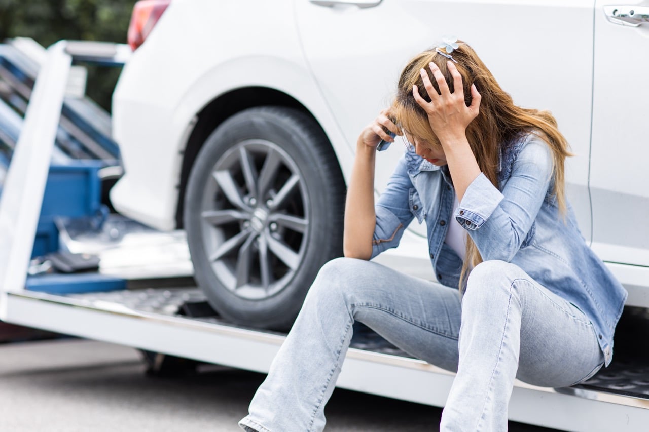 Une jeune femme triste qui découvre que son assurance auto ne couvre pas tous les dégâts de sa voiture