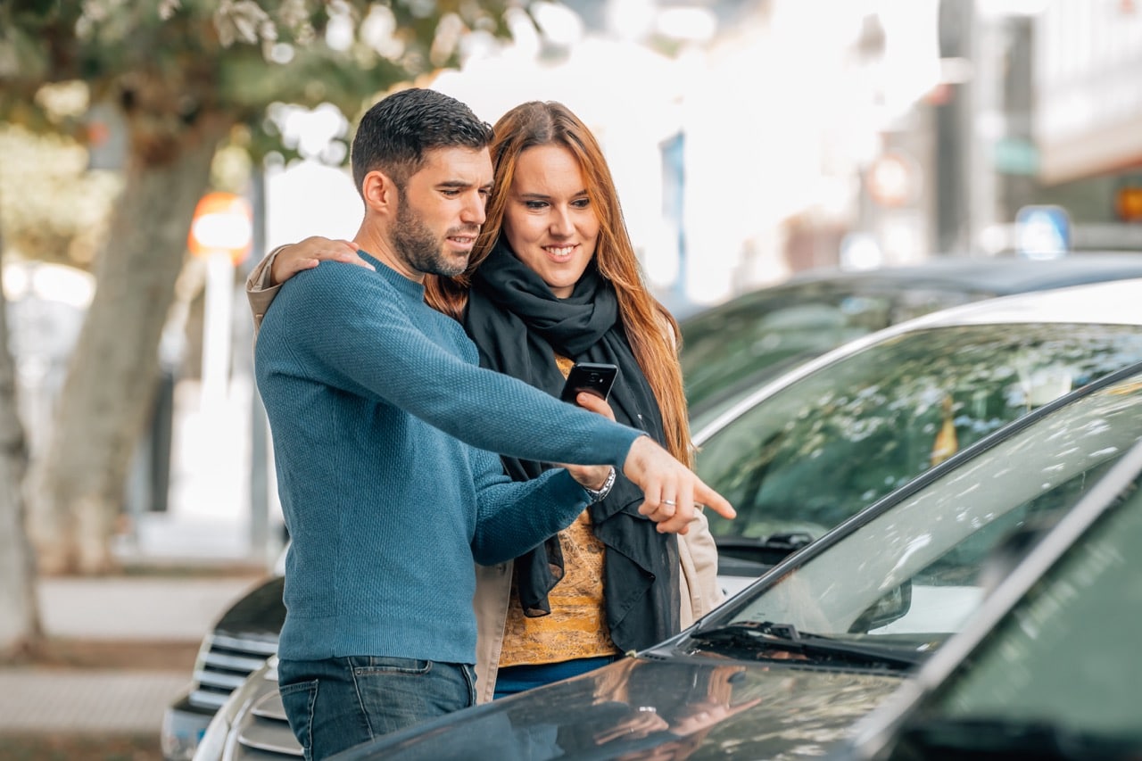 Un couple en train de vérifier une voiture d'un particulier qu'ils veulent acheter