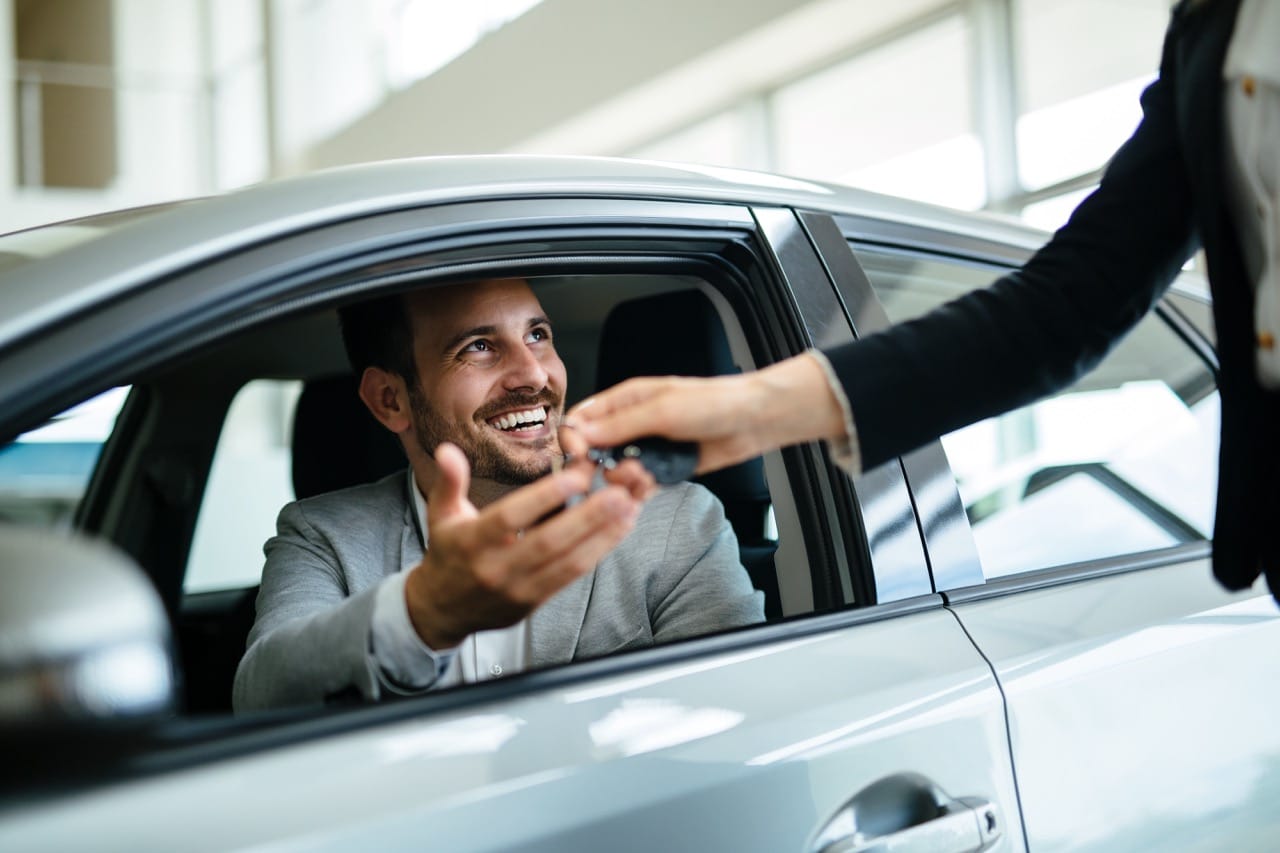 Une homme reçoit sa nouvelle voiture qu'il vient d'acheter moins cher