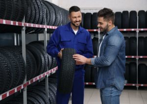 Un vendeur de pneus conseille son client pour le choix d'un nouveau pneu pour sa voiture