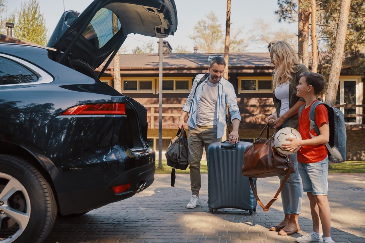 Une famille en train de charger la voiture qu'ils ont louée pour leurs vacances