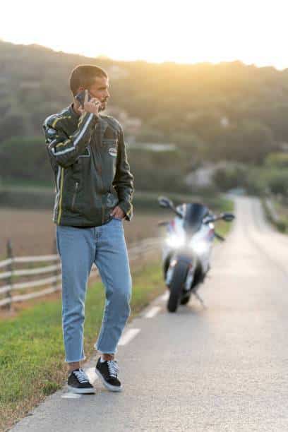 Un motard en panne contact son assurance pour la garantie
