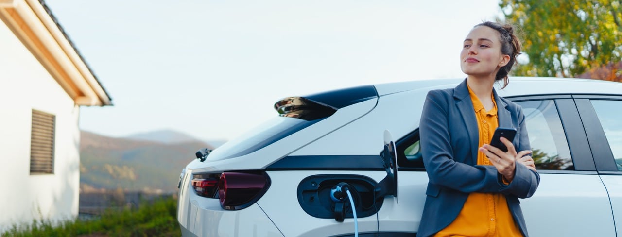 Une femme attend que sa voiture hybride se recharge